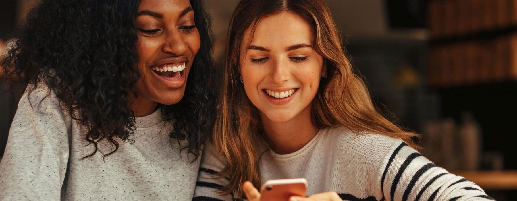 a couple of women looking at a phone